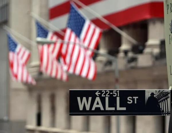 Wall St. street sign with American flags in the background.