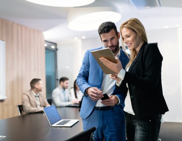 A man and a woman in a business meeting, looking at a tablet together.